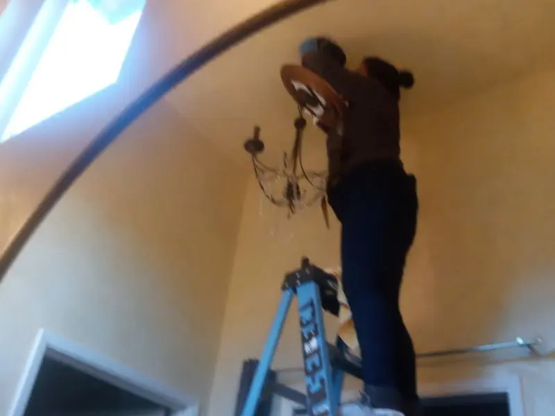 Electrician installing a chandelier in a Camden residence